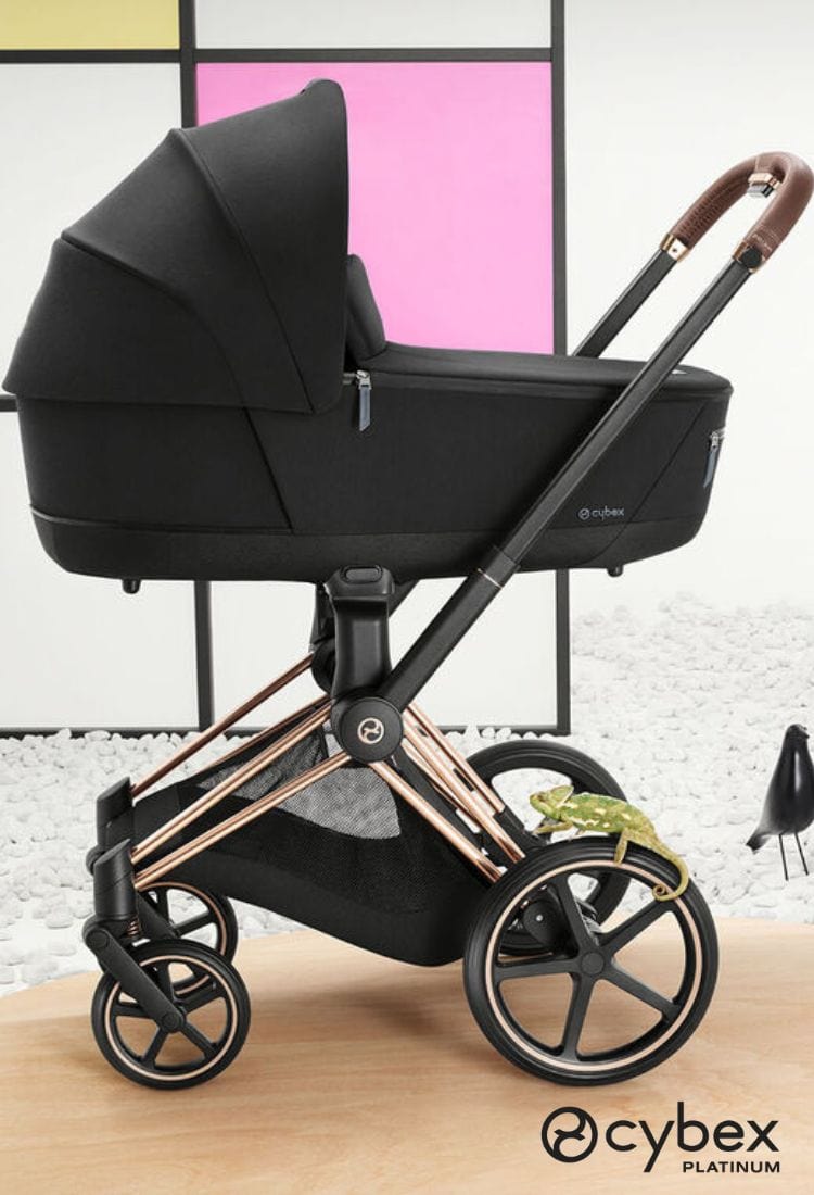 Black Cybex Platinum stroller with rose gold accents on a wooden surface.