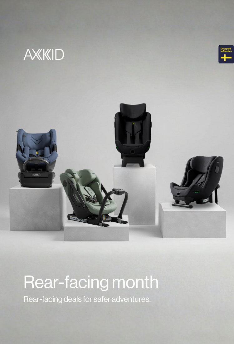 Four child car seats on pedestals with AXKID branding and text about rear-facing safety.